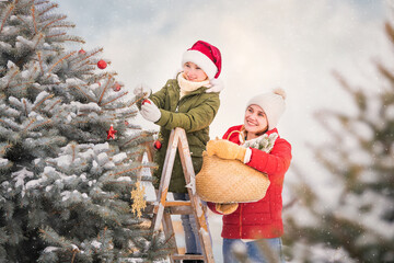mother and the daughter decorate a Christmas tree snowy winter outside