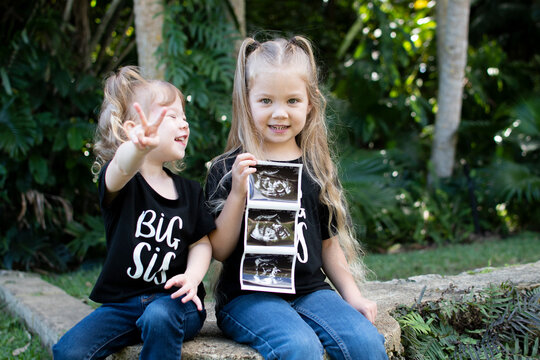 Pregnancy announcement by siblings. Social media pregnancy announcement. Big sister. The third child in a family. Two kids holding a sonogram of a new baby 