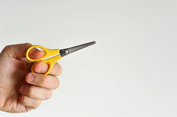 mão segurando tesoura escolar amarela