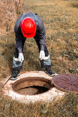The plumber opened the well hatch and leaned over it. Maintenance of septic tanks and wells in rural areas