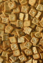 Background texture of small edible squares baked from dough and sprinkled with salt. A lot of salt cracker