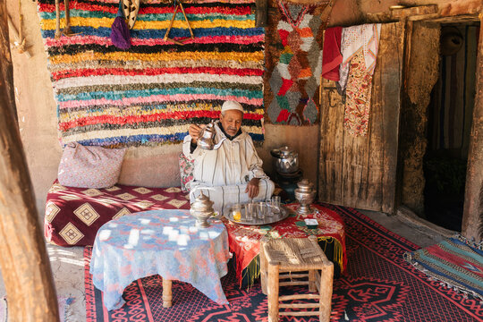 Man in traditional clothes preparing Moroccan tea in cup