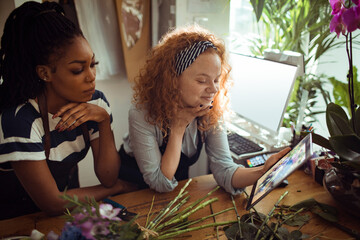 Florists collaborate over digital designs in a flower shop