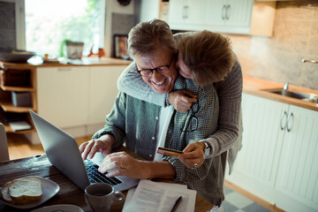 Middle aged couple holding credit card in the kitchen