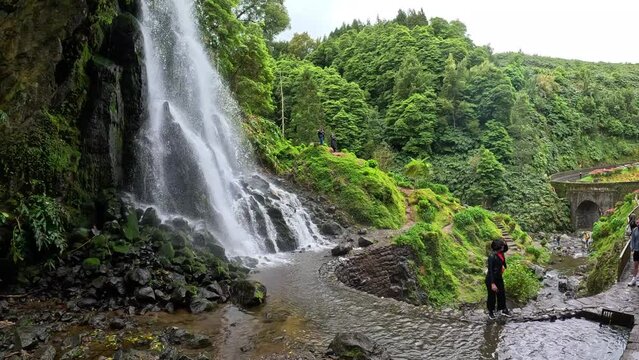 People taking pictures at the Watefall called Cascata da Ribeira dos Caldeirões in the island of Sao Miguel in Azores, Portugal