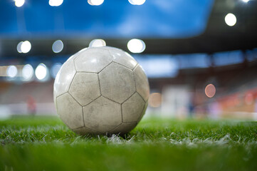 White soccer ball lying on the grass at stadium