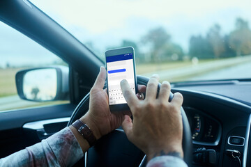 Close up male hands texting on smartphone while driving car