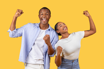 Ecstatic black couple with raised fists in victory