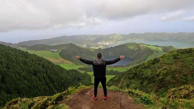 Arms wide open while hiking in a path at the 'Miradouro da Grota do Inferno' next to the volcano and lake of Sete Cidades in the island of Sao Miguel in Azores, Portugal