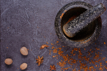 A pestle and mortar with Nutmeg, Star Anise with a pestle and mortar on a dark background. Flat lay, top view with copyspace.