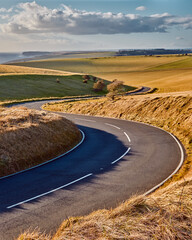 Winding curvy rural road leading through the countryside bathed in warn sunlight in Sussex, England.