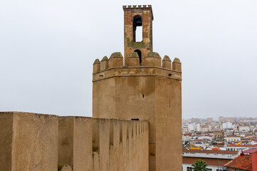 Mysterious Medieval Vibes: Battlemented corridor leading to Espantaperros Tower in Badajoz, shrouded in fog, with the city peeking through the mist.