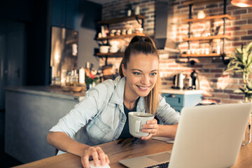 Happy Woman Enjoying Coffee While Working on Laptop at Home