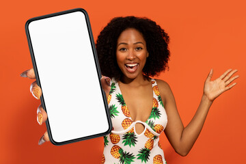 African lady in swimwear, showcasing large phone touchscreen over orange