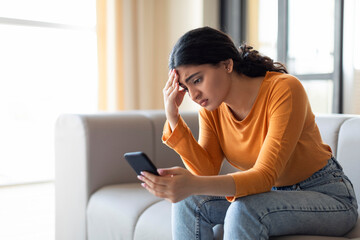 Bad News. Upset Indian Woman Reading Message On Smartphone At Home