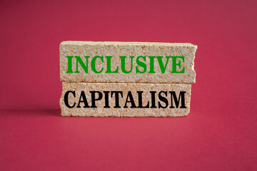 Concept green words Inclusive capitalism on beautiful brick blocks. Beautiful red background. Business inclusive capitalism concept. Copy space.