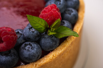 close-up of cheesecake decorated with fresh berries, blueberries and raspberries and mint leaves. confectionery, baking, bright colors