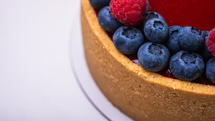 top view, close-up of cheese cheesecake decorated with fresh berries, blueberries and raspberries on light background, place for text
