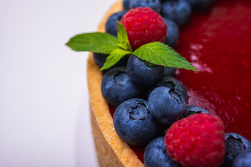 close-up of cheesecake decorated with fresh berries, blueberries and raspberries and mint leaves. confectionery, baking, bright colors