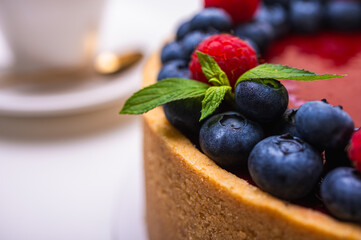 close-up of cheesecake decorated with fresh berries, blueberries and raspberries and mint leaves. confectionery, baking, bright colors