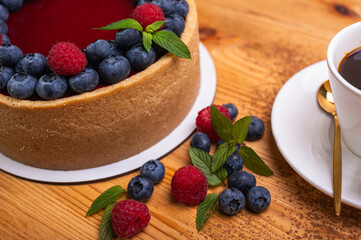 close-up of cheesecake decorated with fresh berries, blueberries and raspberries and mint leaves. confectionery, baking, bright colors	
