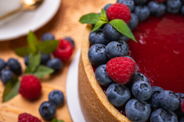 close-up of cheesecake decorated with fresh berries, blueberries and raspberries and mint leaves. confectionery, baking, bright colors