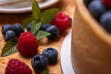 close-up of cheesecake decorated with fresh berries, blueberries and raspberries and mint leaves. confectionery, baking, bright colors