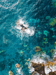 Shore reefs with waves crashing and white foaming, aerial top down, vertical shot