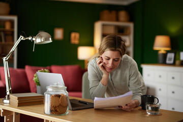 Mid adult woman examining her bank statement at home office