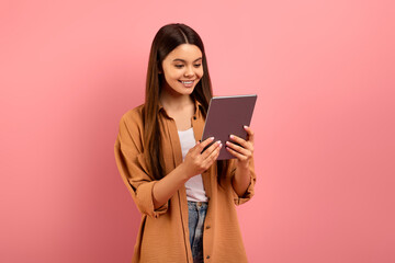 Smiling teen girl looking at digital tablet screen with interest,