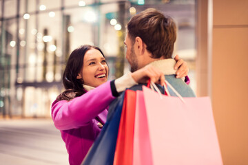 couple with Xmas shopping bags embracing outside of city mall