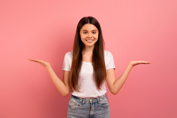 Joyful teen girl in casual clothes demonstrating something on her empty palms