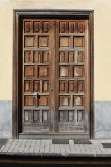 Wooden door yellow paint wall. Spanish european architecture background. Pavement and street. Urban background. Wooden door house entrance. Retro antique home facade.