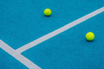 blue paddle tennis court with two balls on the surface