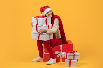 lady holding many Xmas presents sitting on gift box, studio