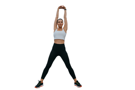 Purposeful sporty multi ethnic girl in sporty leggings, sneakers, stretching against transparent backgroundk. Warming up before exercise, rises hands up looks forward. Fitness, sport, active lifestyle