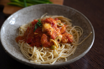 Spaghetti with tomato and olives sauce in a bowl