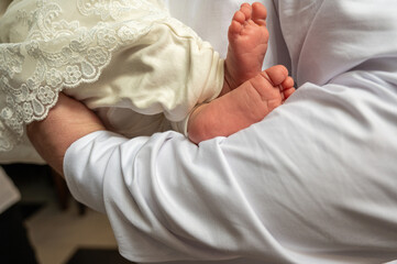 a man holds a small child in his arms, before baptism. The legs of a small child