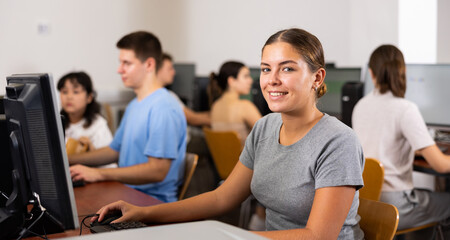 Portrait of smiling girl student looking at camera during lesson in computer class in college