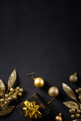 Naklejka premium Christmas gold decorations and present box on black. Flat lay image with copy space.