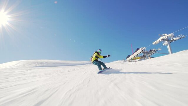 girl snowboarding on slopes. female snowboarder in european ski center. front view. clear blue sky.