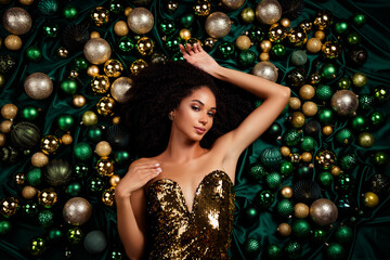 High angle view portrait of attractive lady posing lying among golden green christmas tree shiny baubles advert