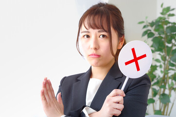 バツのプレートを示すキャリアウーマン