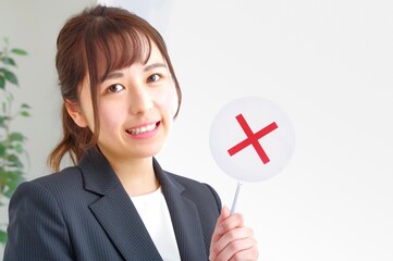 バツのプレートを示すキャリアウーマン