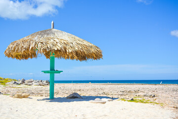 Thatched hut on a stretch of beach in Aruba overlooking the Caribbean Sea. Beautiful Caribbean summer seascape scene. Space for text.  © Lara Red