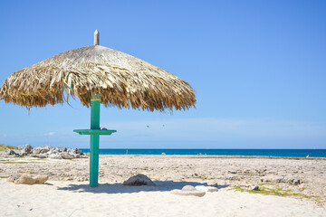 Thatched hut on a stretch of beach in Aruba overlooking the Caribbean Sea. Beautiful Caribbean summer seascape scene. Space for text. 