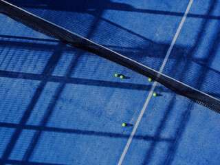 drone view of a paddle tennis court net and five balls