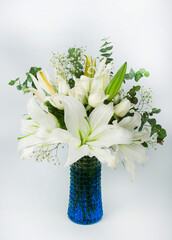 A vertical image of a beautiful all white bouquet of lily, eucaliptus leaves and baby' s breath in...