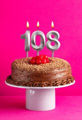 Number 108 candle - Chocolate cake on pink background