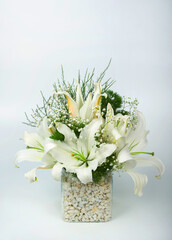 A vertical image of a beautiful bouquet of white lilies in a glass vase on isolated on white background